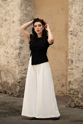 a lady in a black asymmetrical top and a pair of white wide leg pants